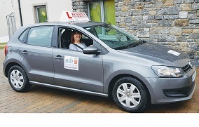Side view of the Kennedy School of Motoring car with Rita Kennedy in the driver's seat.